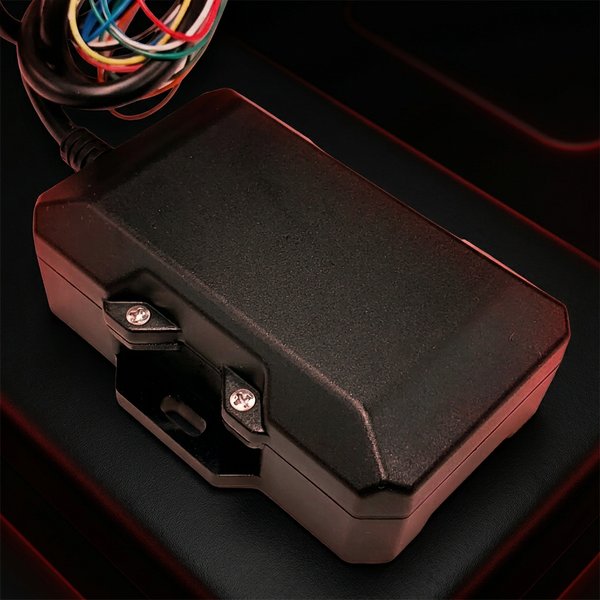 TTU-2830 — black hard-wired asset tracking module with side mounting brackets and a multicolored wiring harness, photographed on a dark red-accented background.
